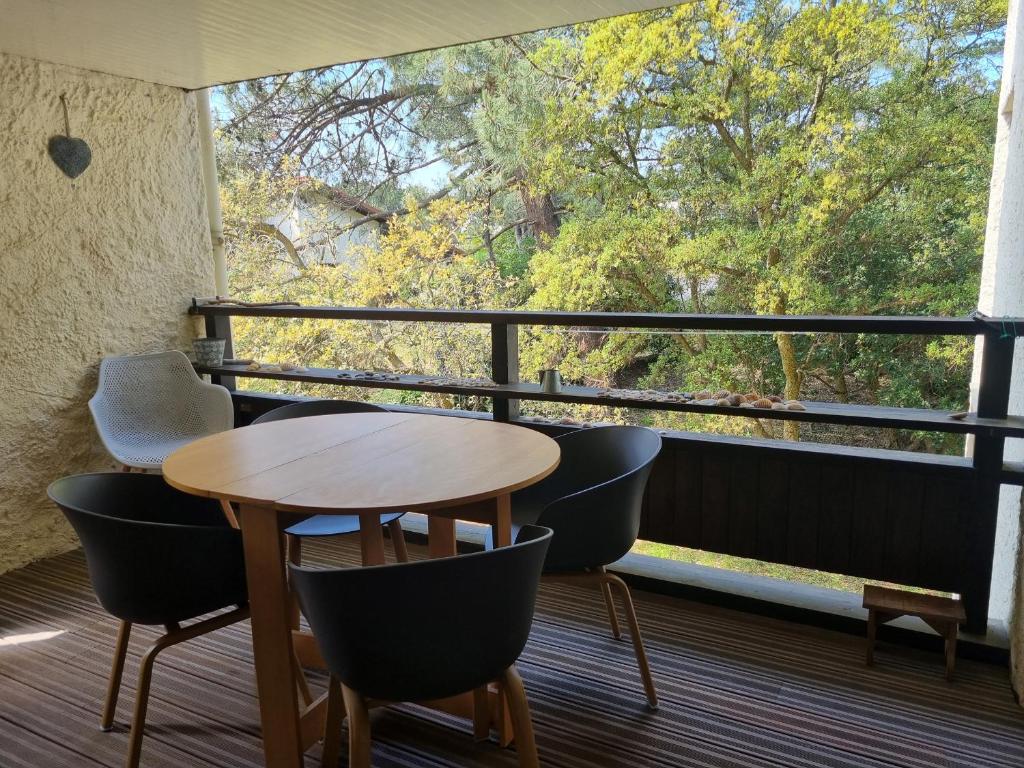 una mesa y sillas en un balcón con vistas a los árboles en Appartement Seignosse, 3 pièces, 5 personnes - FR-1-239-959, en Seignosse