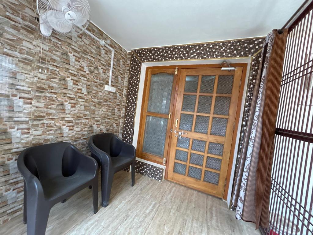 duas cadeiras pretas num quarto com uma porta em Ayodhya Tours em Faizābād