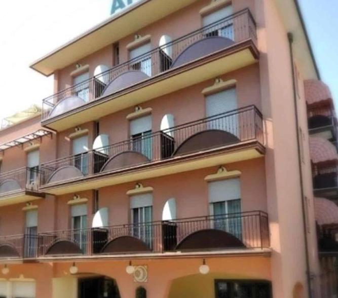 un bâtiment rose avec des balcons sur son côté dans l'établissement Hotel Anita, à Gatteo a Mare
