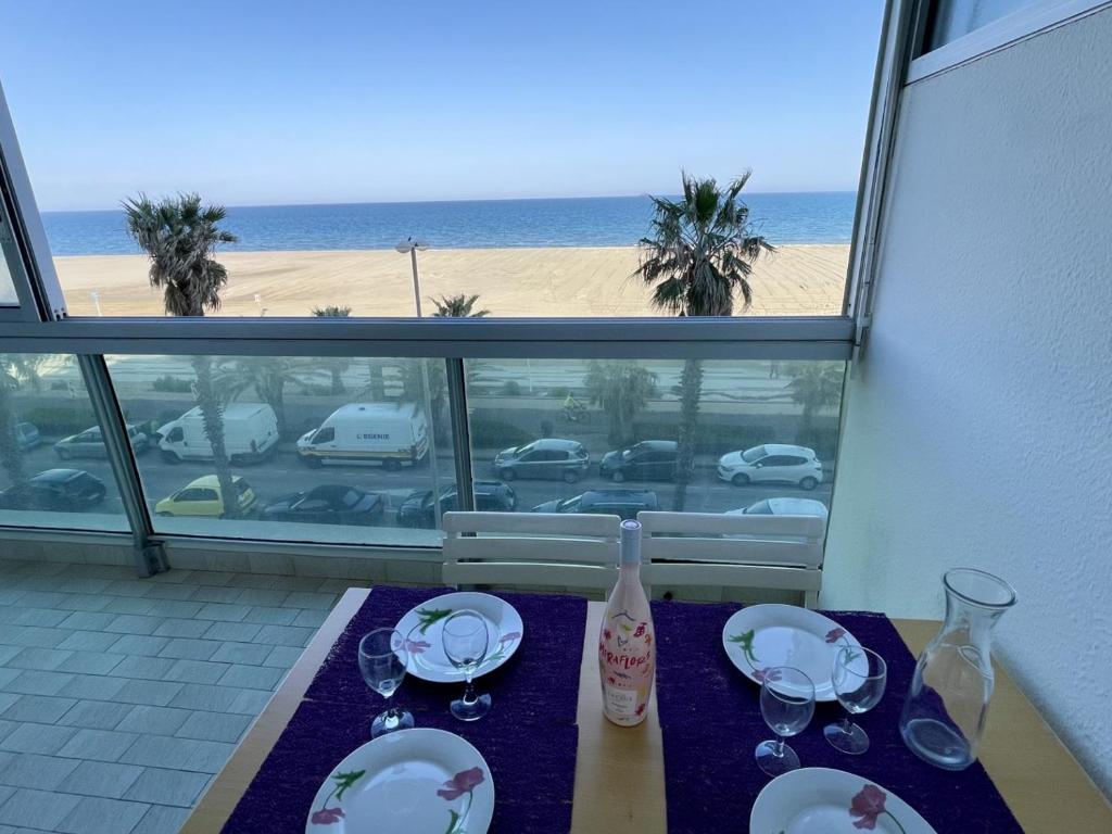- une table avec des assiettes et des verres à vin et une vue sur la plage dans l'établissement Studio cabine avec parking, Canet-en-Roussillon - FR-1-748-2, à Canet