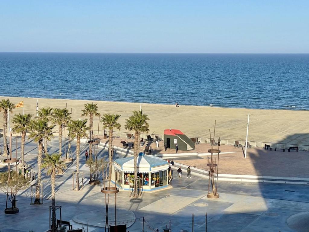 - une plage avec un bâtiment, des palmiers et l'océan dans l'établissement Appartement rénové avec piscine commune, 4 couchages, climatisé, wifi, terrasse vue mer - FR-1-748-3, à Canet