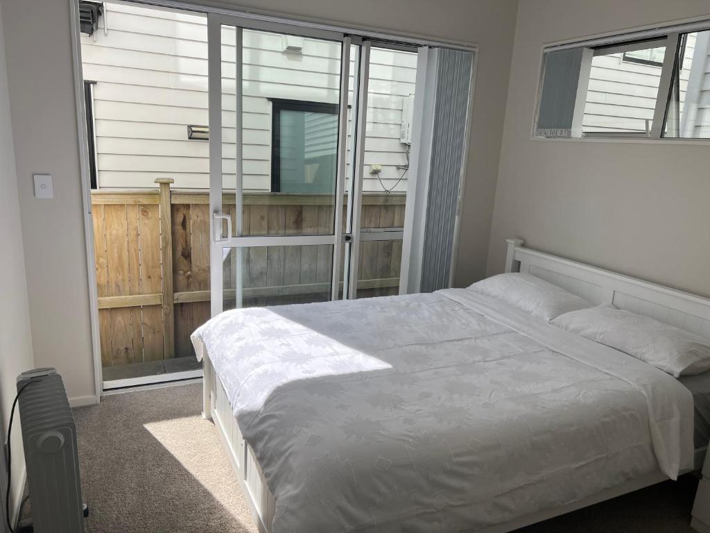 a bedroom with a white bed and a window at Private Ensuite for singles or couples in Auckland