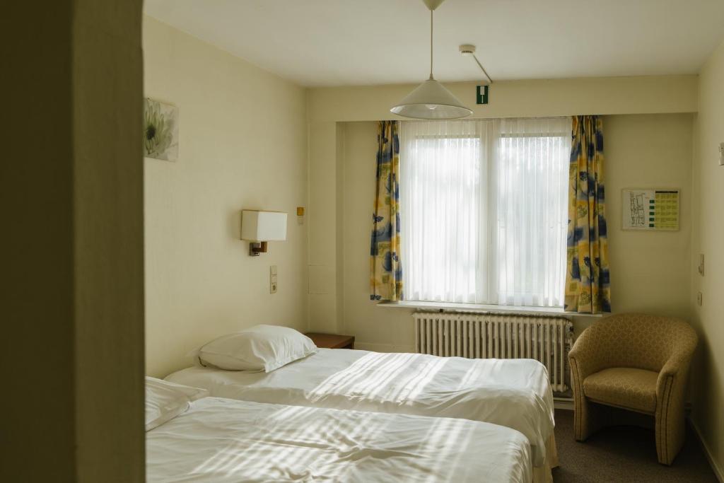 1 dormitorio con 1 cama, 1 silla y 1 ventana en Hotel Kempenrust en Kasterlee