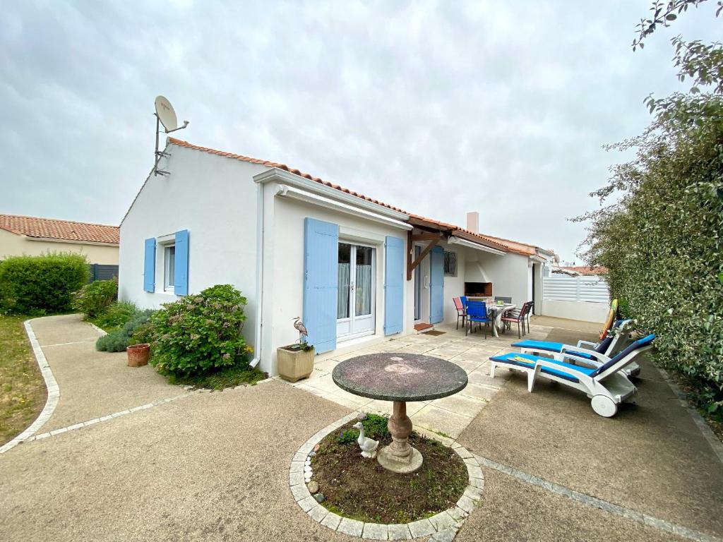 un patio con mesa y sillas frente a una casa en Maison Bretignolles-sur-Mer, 4 pièces, 5 personnes - FR-1-231-323, en Bretignolles-sur-Mer