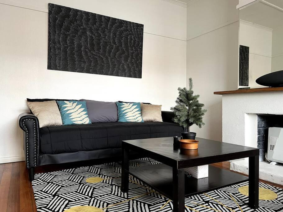 a living room with a black couch and a table at Princes Cottage In Prahran, On Chapel St in Melbourne