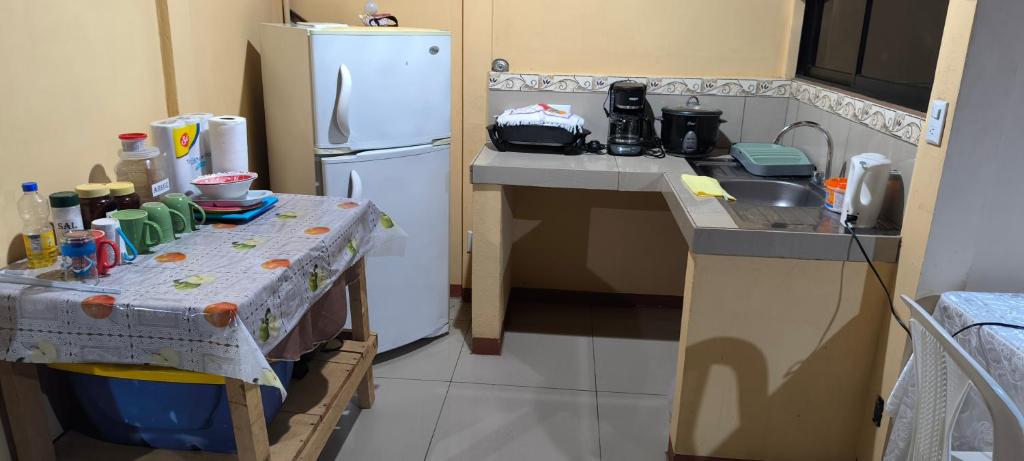 a small kitchen with a table and a white refrigerator at CASA DE CAMPO in Turrialba