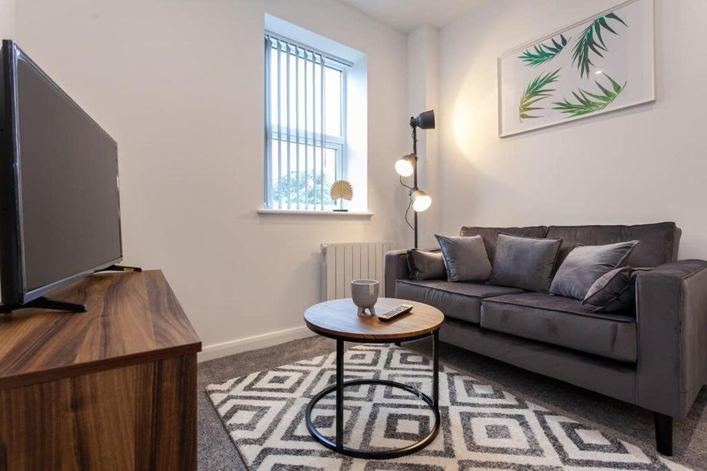 Fantastic 1 Bedroom Apartment in Bolton في بولتون: غرفة معيشة مع أريكة وطاولة