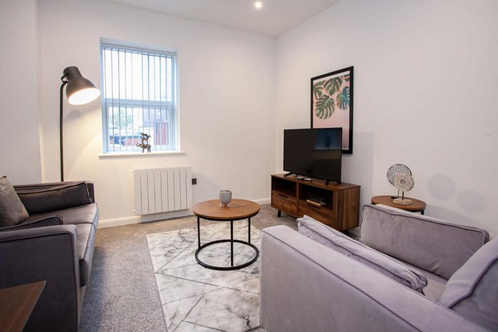 a living room with a couch and a tv and a table at Modern 1 Bedroom Apartment in Bolton in Bolton