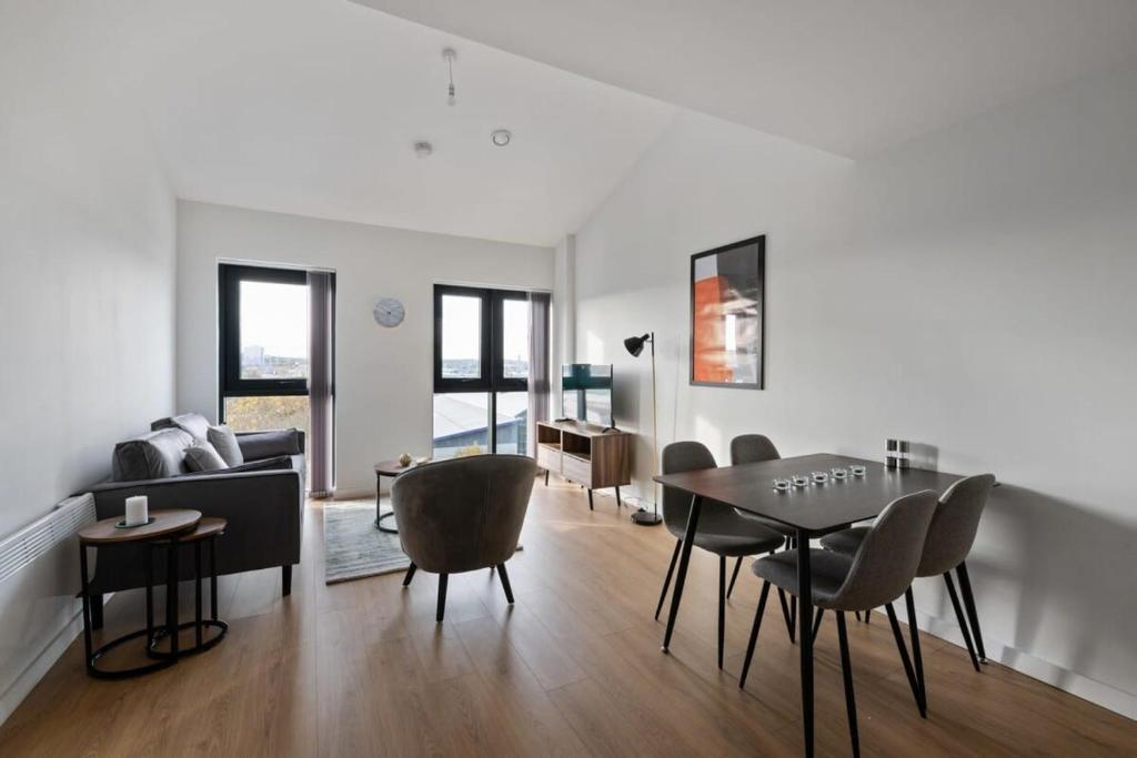 a living room with a table and chairs and a couch at Beautiful 2 bedroom apartment in a converted mill in Leeds