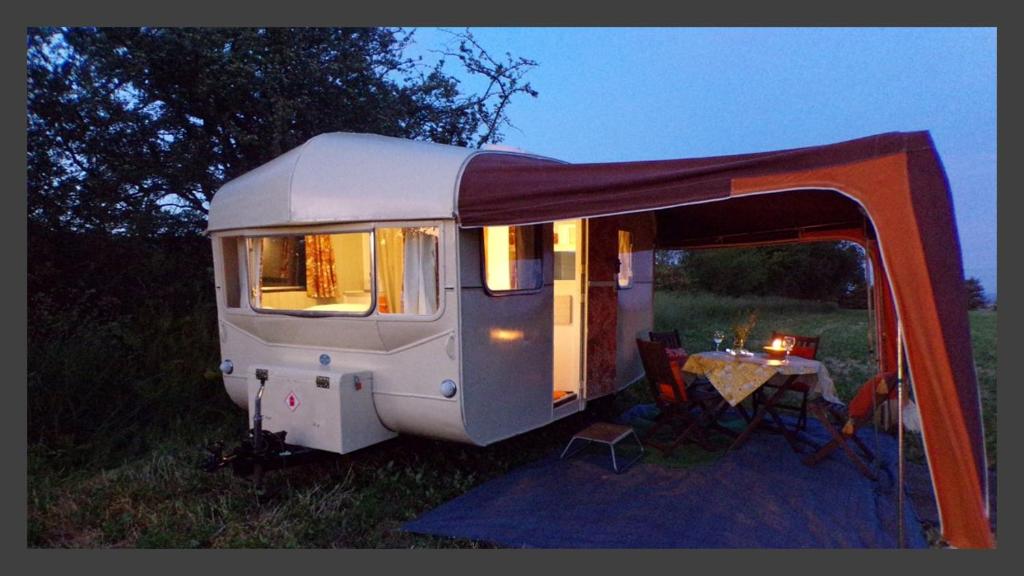 a white caravan with a table in a field at Retro Caravan with Mountain Views in Abergavenny