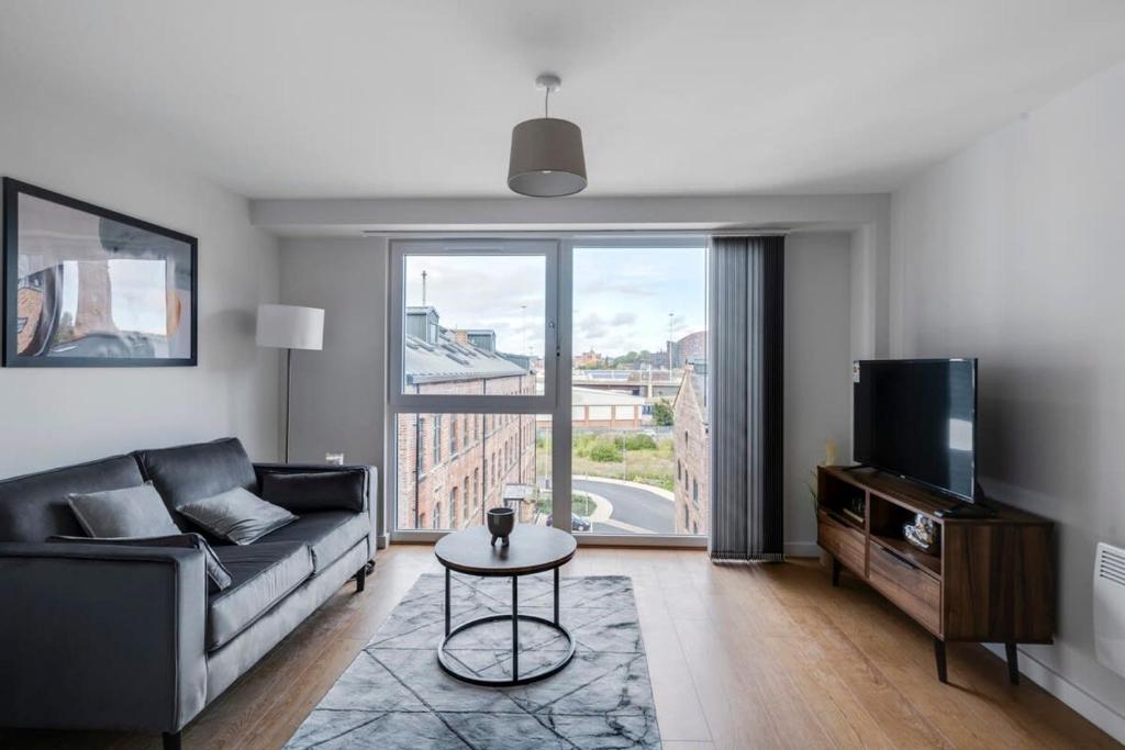 a living room with a couch and a tv at Spacious 1 Bedroom Apartment in a Converted Mill in Leeds