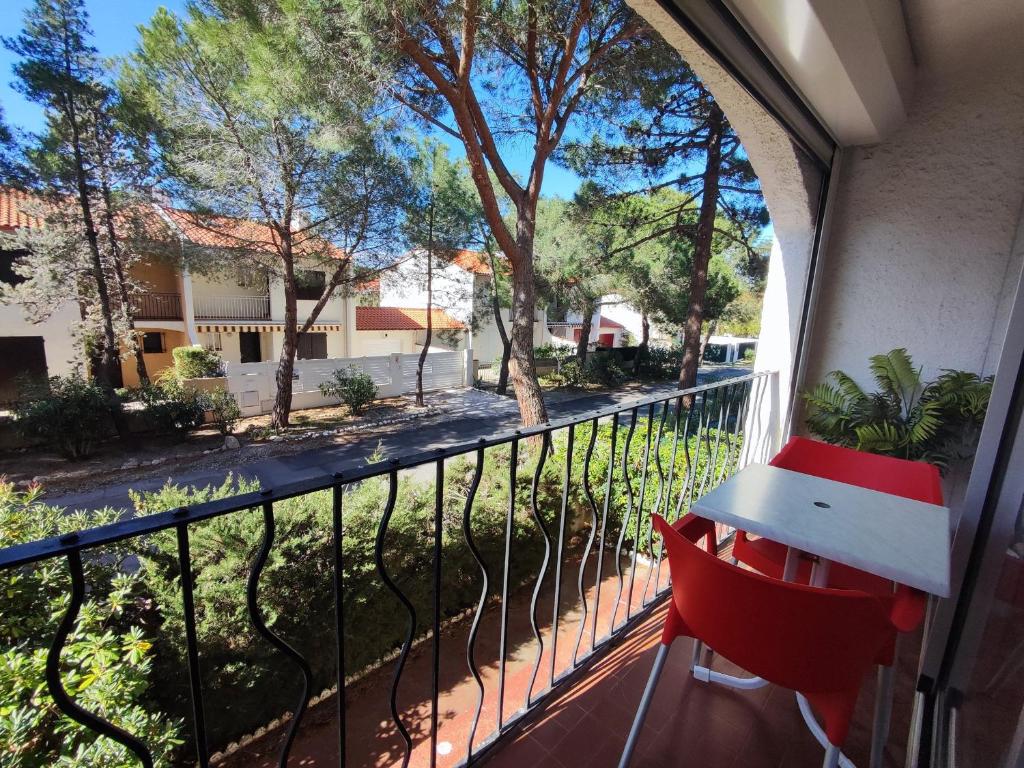 un fauteuil rouge sur un balcon avec vue sur une rue dans l'établissement Appartement 2 Pièces à Argelès-sur-Mer, à 300m de la Plage avec Piscine, Tennis et Animaux Acceptés - FR-1-776-48, à Argelès-sur-Mer