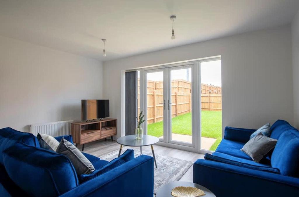 uma sala de estar com dois sofás azuis e uma janela em Lovely brand new 3 bedroom city centre house with garden em Derby