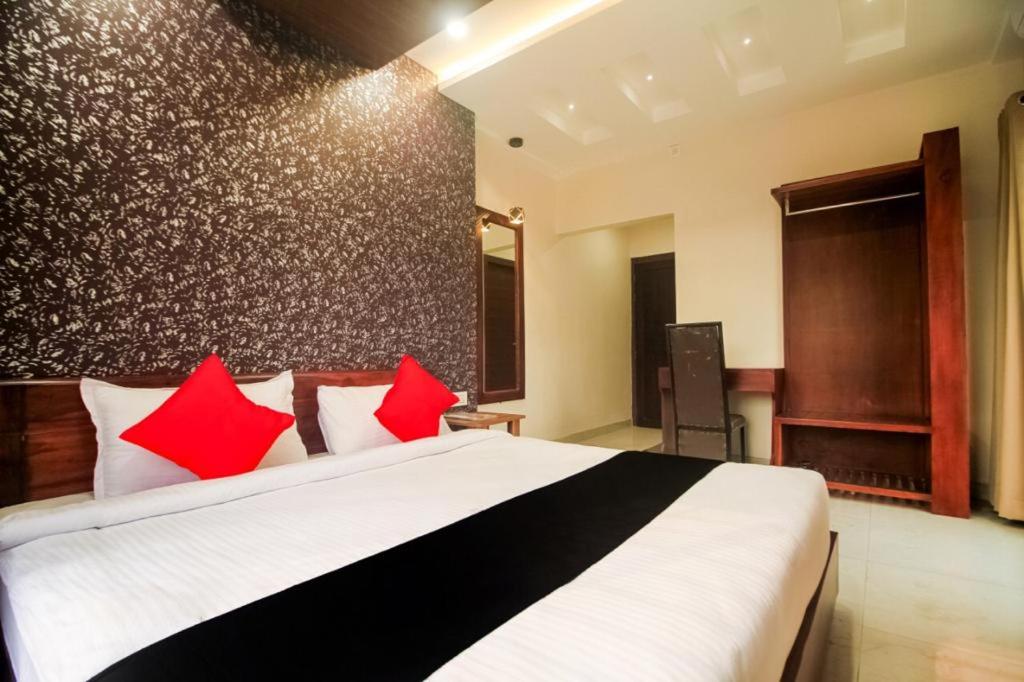 a bedroom with a large white bed with red pillows at HOTEL GRAND PALACE & BANQUET in Siliguri