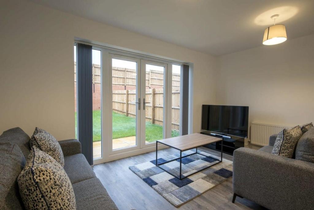 een woonkamer met een bank en een televisie bij Modern 3 Bedroom House in Central Derby in Derby