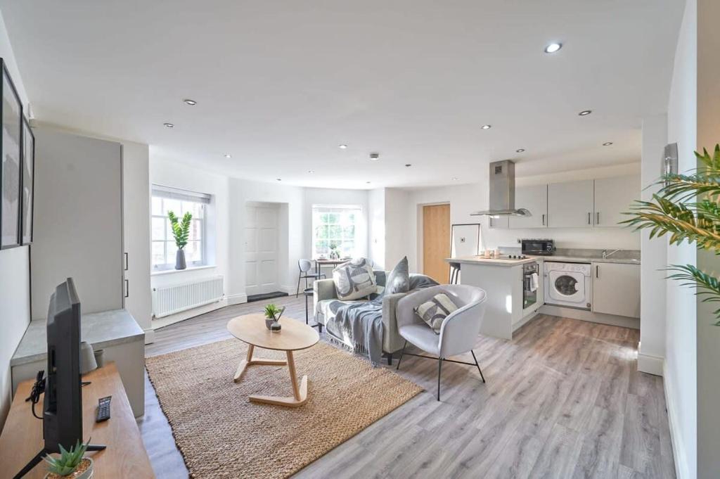 A Stylish Apartment with Parking in Preston في بريستون: غرفة معيشة مع أريكة وطاولة ومطبخ