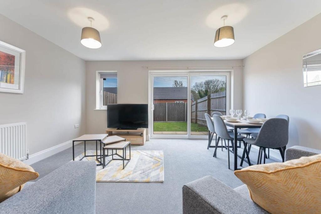 a living room with a table and chairs and a tv at Spacious 3 Bedroom House with Garden in Birmingham in Birmingham