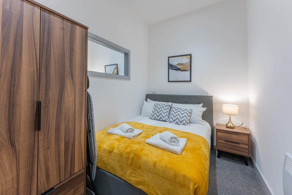 a bedroom with a bed with yellow sheets and a wooden cabinet at Modern 1 Bedroom Apartment in Dudley in Brierley Hill