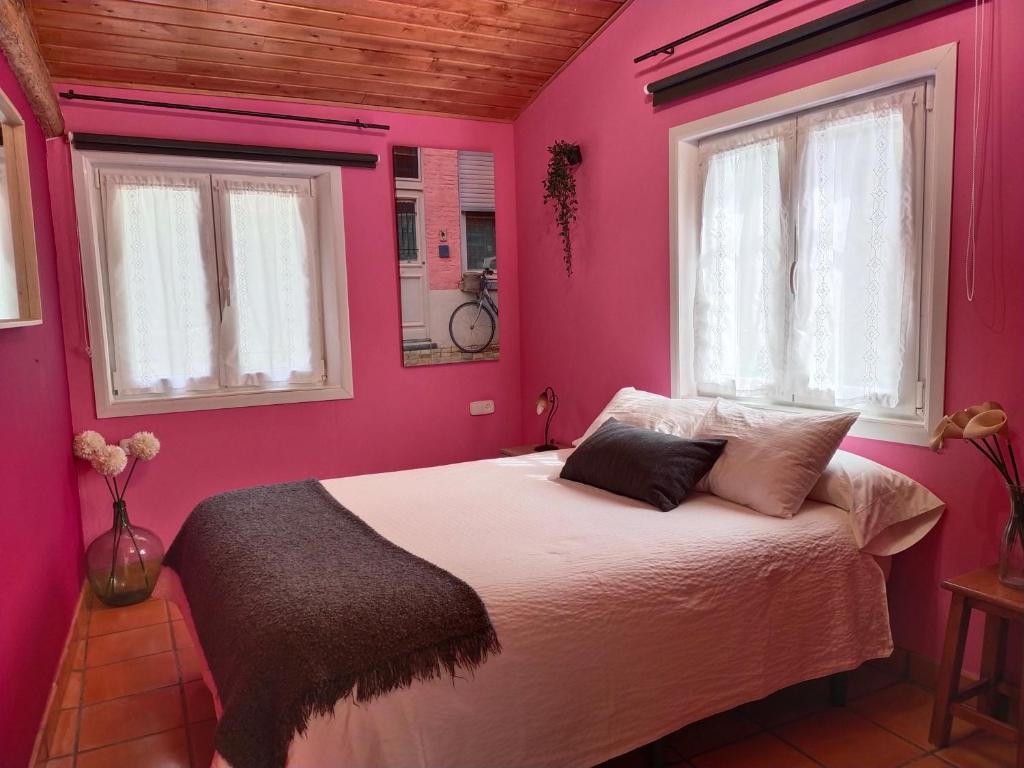 um quarto cor-de-rosa com uma cama e 2 janelas em ANTZOMENDI em Mutriku