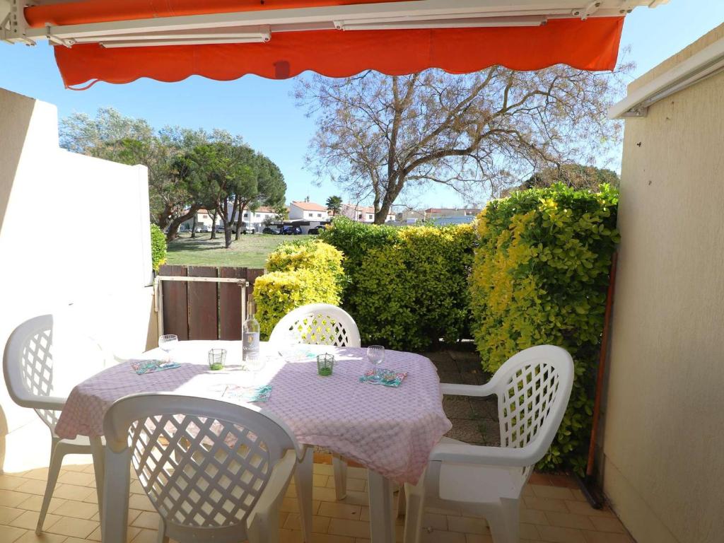 une table et des chaises blanches sur une terrasse avec une table et des chaises dans l'établissement Appartement 2 Pièces Cabine en Rez-de-Jardin avec Parking, à 300m de la Plage, Animaux Admis - FR-1-307-257, au Grau-du-Roi