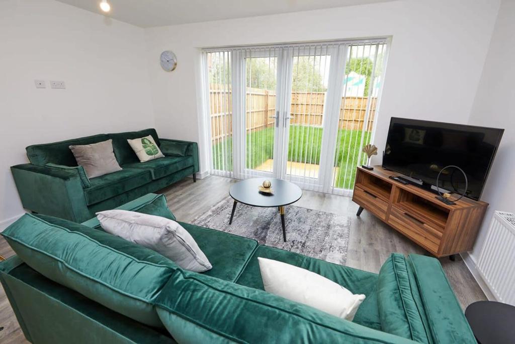 een woonkamer met een groene bank en een televisie bij Beautiful brand new 3 bedroom city centre house with garden in Derby