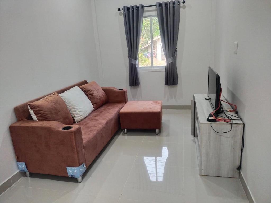 a living room with a brown couch and a television at Family house villa in Ban Khlong Khamao (2)