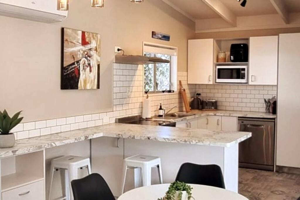 eine Küche mit weißen Schränken und einer Marmoroberfläche in der Unterkunft Ultimate Family Holiday - Pet Friendly! in Papamoa
