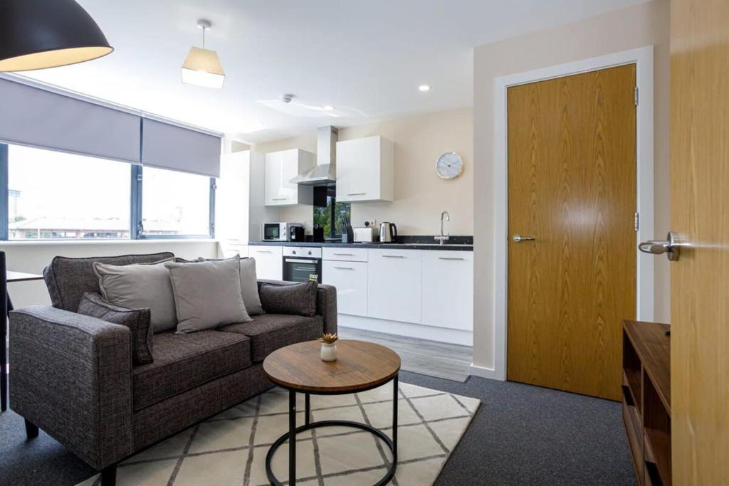 uma sala de estar com um sofá, uma mesa e uma cozinha em Modern and Stylish 1 Bed Apartment Manchester em Manchester