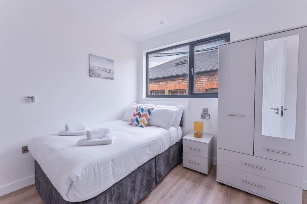 a white bedroom with a large bed and a window at Modern and Bright Studio in Central Sheffield in Sheffield