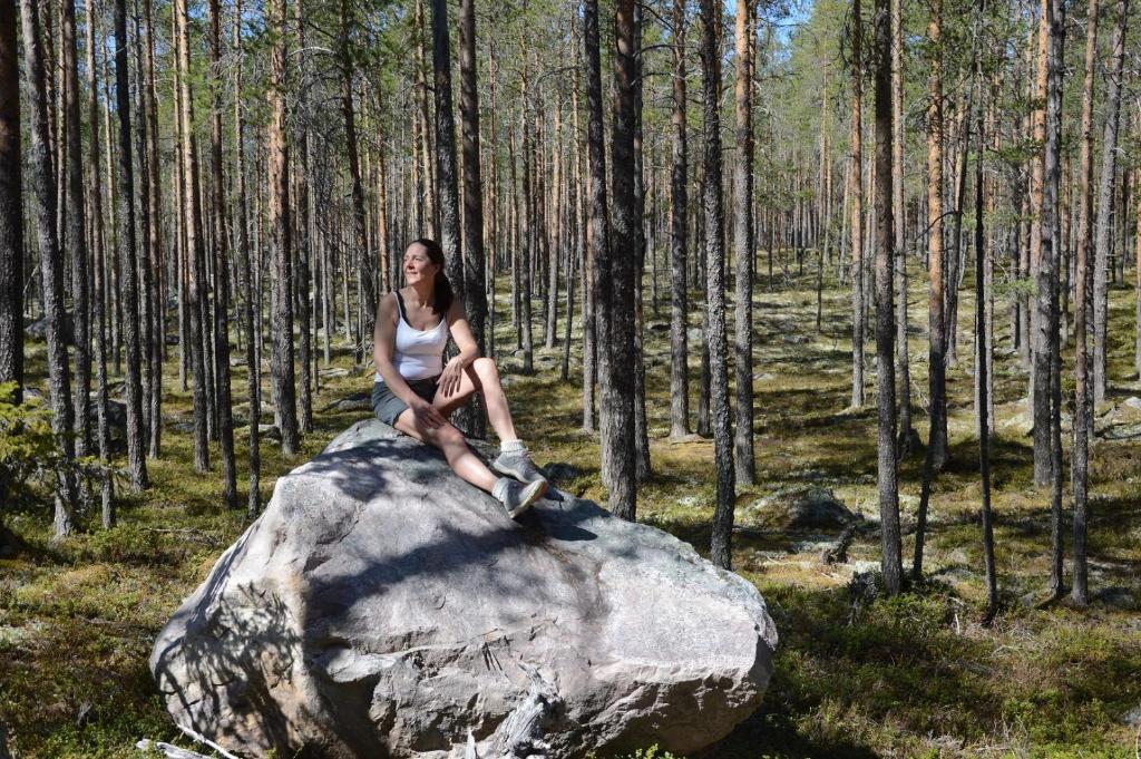 una mujer sentada en una roca en un bosque en 16-Nasjonalpark, sykling, fisking, kanopadling, skogs- og fjellturer en Ljørdal