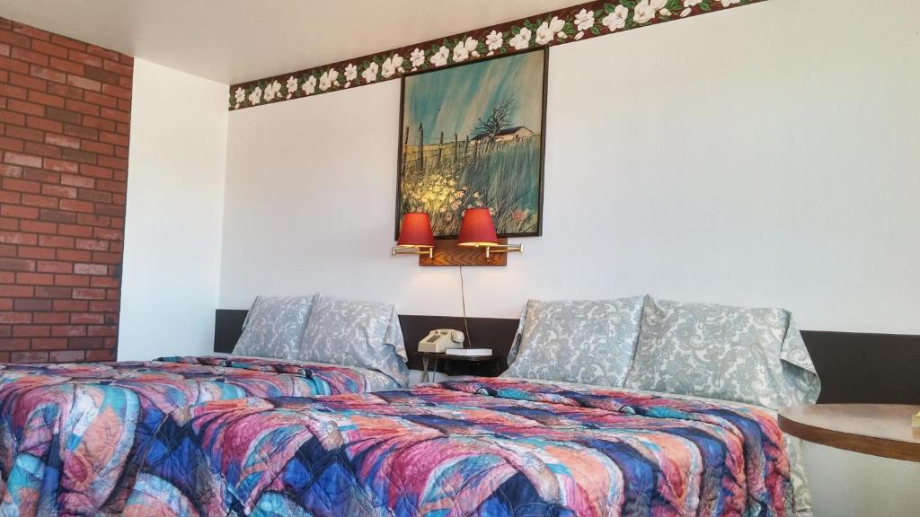 a bedroom with two beds and a painting on the wall at American Inn Motel Canon City in Canon City