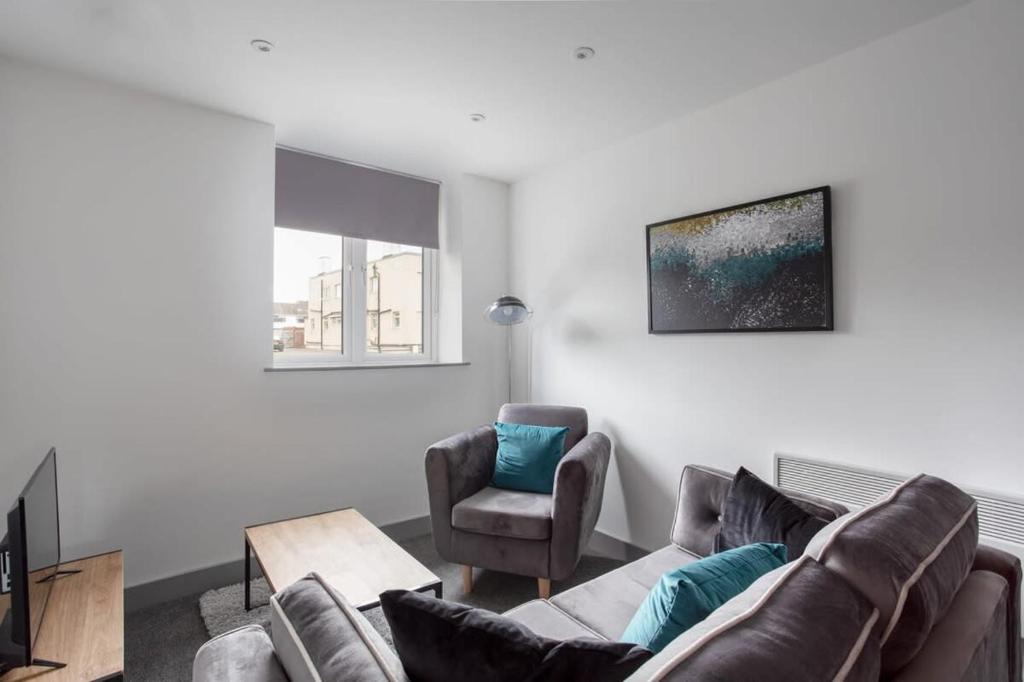 uma sala de estar com um sofá e uma cadeira em Cosy 1 Bedroom Apartment in Leeds em Leeds