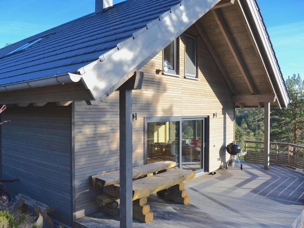 una casa con un banco de madera en una terraza en "NisseHus" Comfortable holiday residence, en Gjerstad