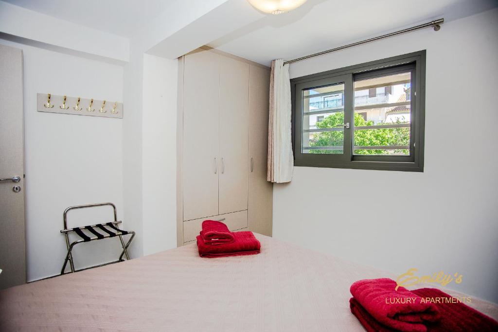 阿爾戈斯托利的住宿－EMILY'S LUXURY APARTMENTS/ GARDEN，一间卧室配有一张带红色枕头的床和一扇窗户