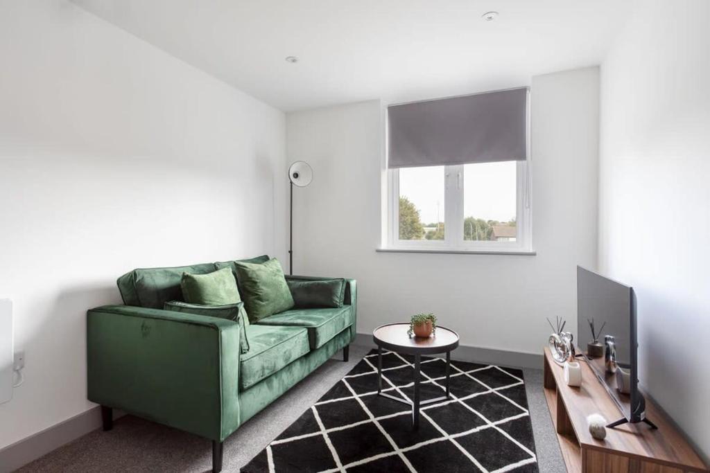 ein Wohnzimmer mit einem grünen Sofa und einem Tisch in der Unterkunft Cosy & Modern 1 Bed Apartment Leeds in Leeds