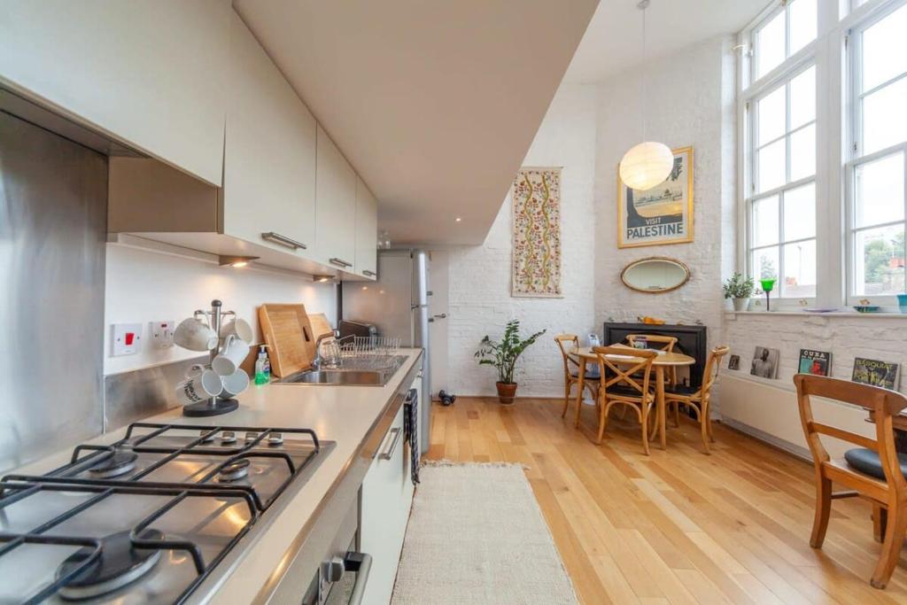 Il comprend une cuisine équipée d'une cuisinière et d'une table avec des chaises. dans l'établissement Charming 1 Bedroom Apartment in old School House, à Londres