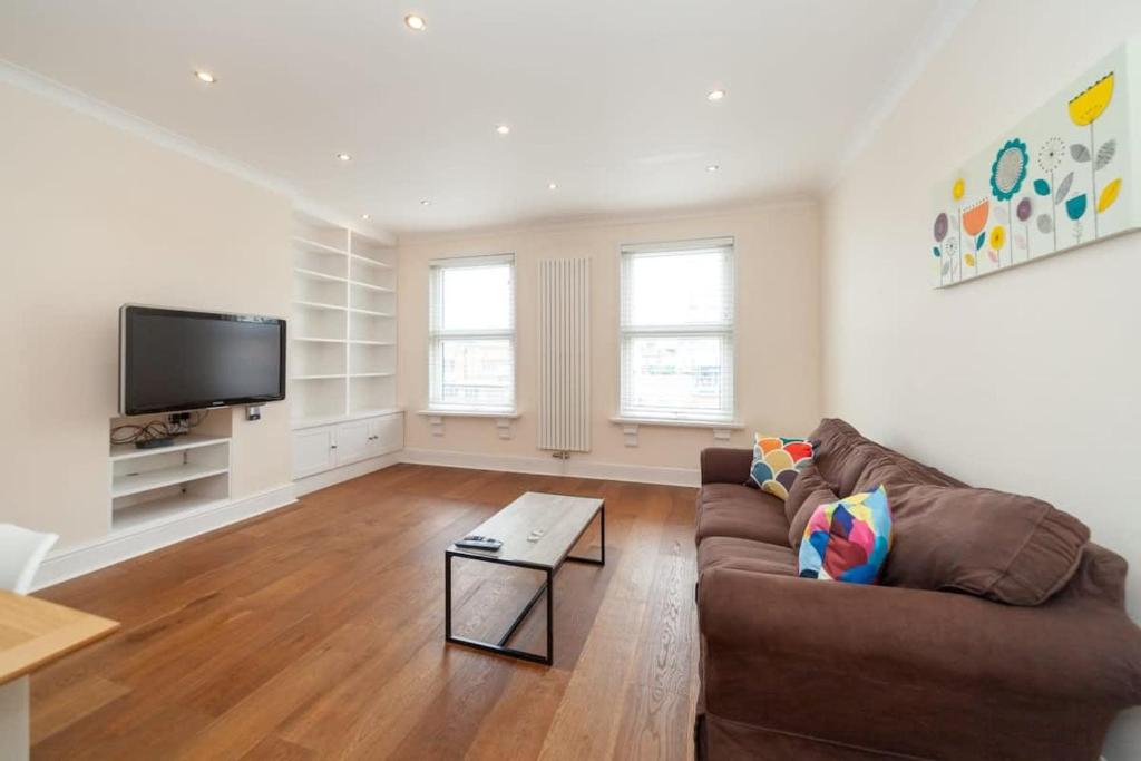 a living room with a couch and a flat screen tv at Spacious 2 Bedroom Maisonette in Stratford in London