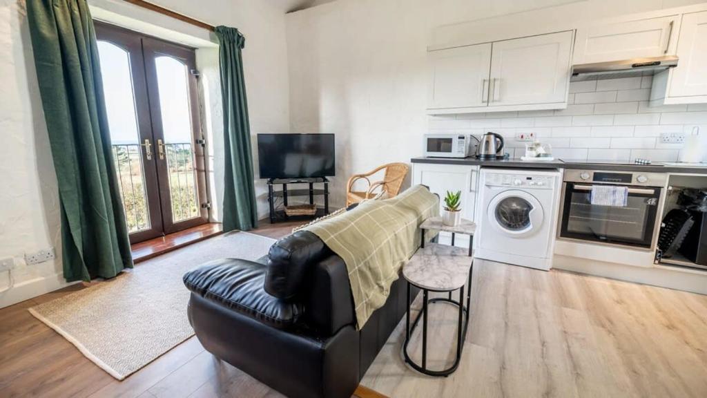 a living room with a couch and a kitchen at Lovely 2 Bedroom Coastal Cottage near Bude in Bude
