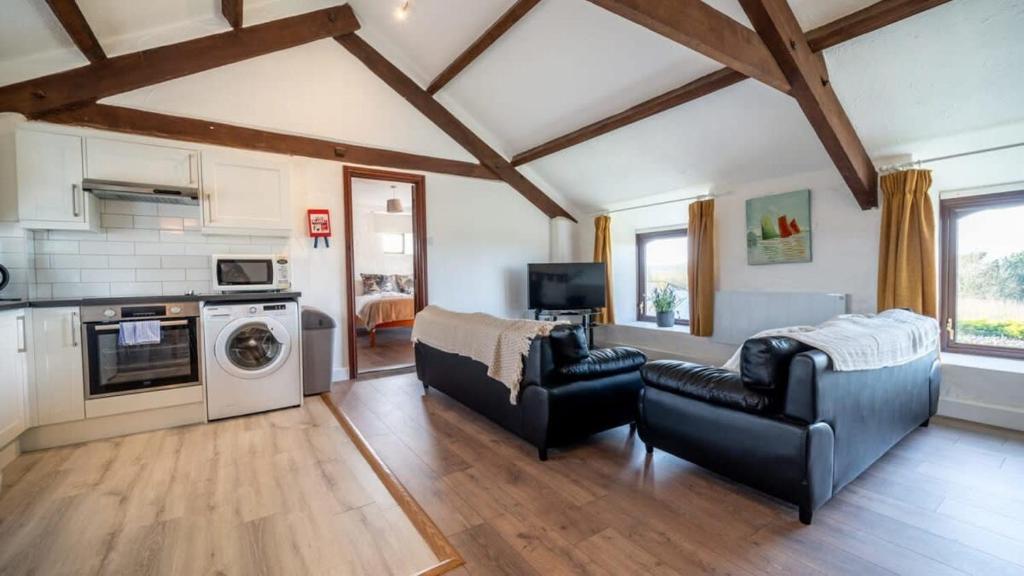 a living room with two couches and a kitchen at Lovely 3 Bedroom Holiday Cottage nr Bude in Bude