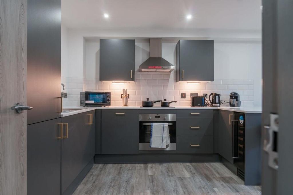 a kitchen with gray cabinets and a stove top oven at Lovely 1 Bedroom Apartment in Preston in Preston