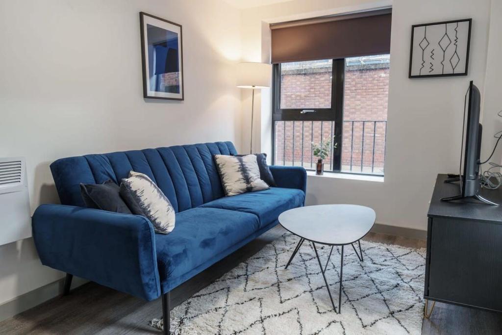 a blue couch in a living room with a table at Lovely 1 Bed Apartment in Liverpool Centre in Liverpool