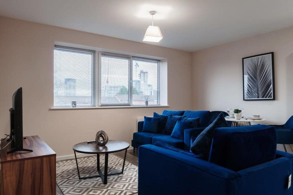 un salon avec un canapé bleu et une télévision dans l'établissement A Lovely Modern 1 Bed Apartment in Manchester, à Manchester