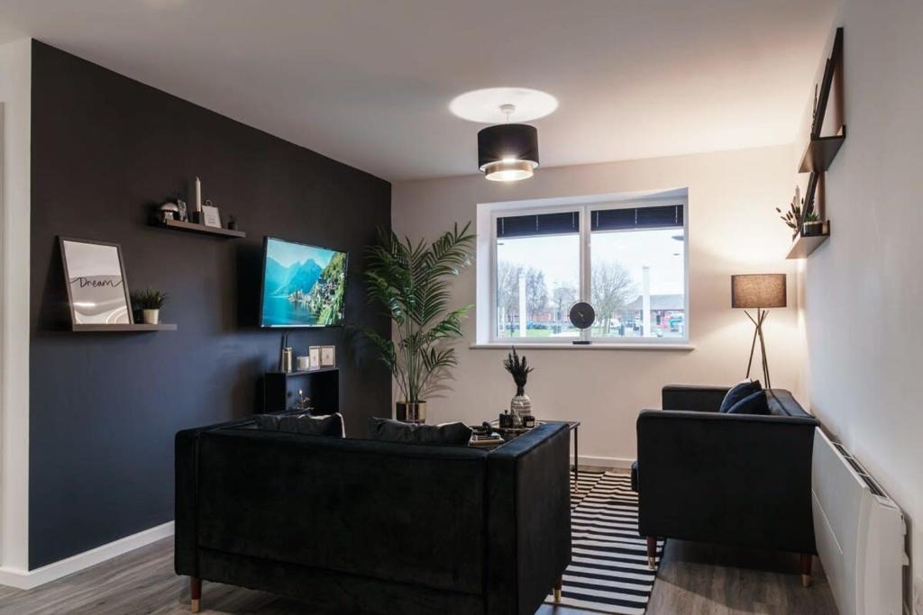 a living room with a black couch and a window at Lovely 2 Bed Apartment in Manchester - Sleeps 4 in Manchester
