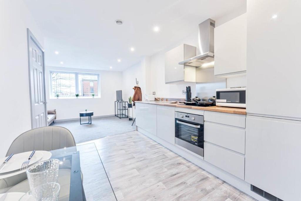 a kitchen with white cabinets and a glass table at Contemporary 1 Bed Apartment in Central Wolverhampton in Wolverhampton