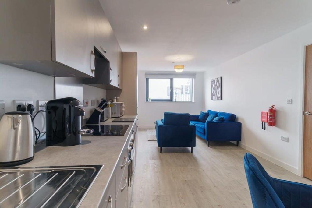 cocina y sala de estar con sofá azul en Stunning 2 Bed Apartment in Salford with Views, en Mánchester