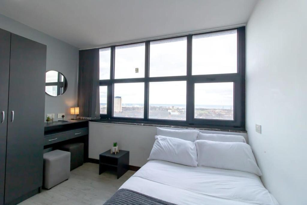 um quarto com uma cama e uma secretária com janelas em Budget Sunderland Studio with Lovely Views em Sunderland