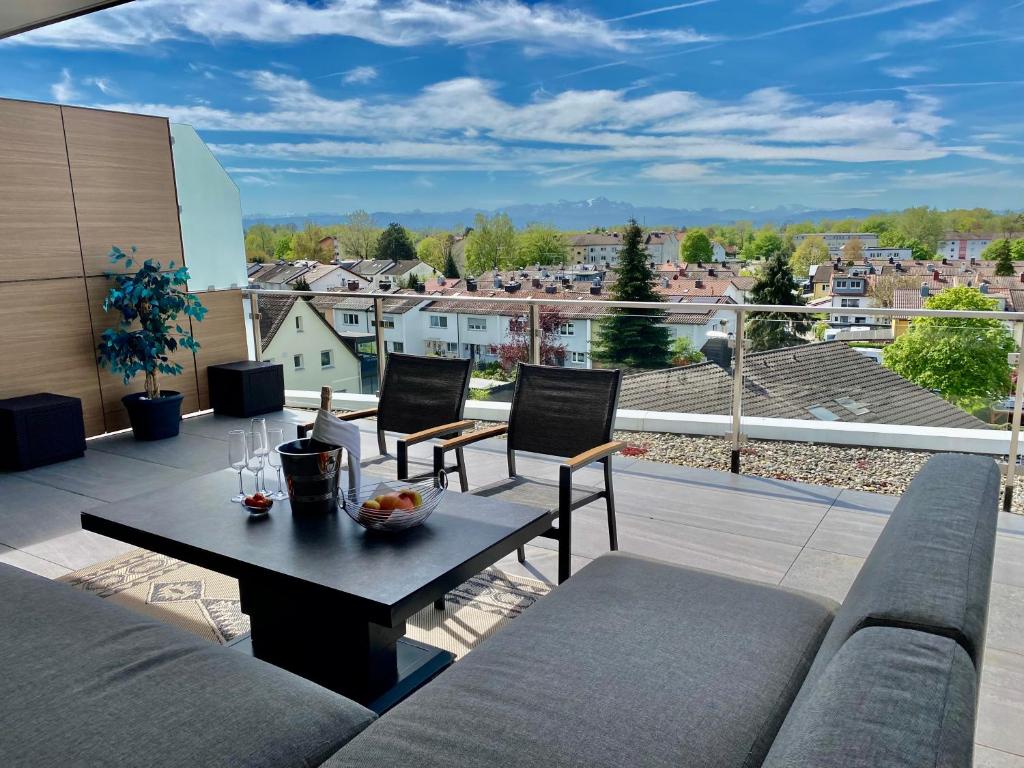 ein Wohnzimmer mit einem Sofa und einem Tisch auf dem Balkon in der Unterkunft Penthouse Apartment mit Alpenblick in Friedrichshafen