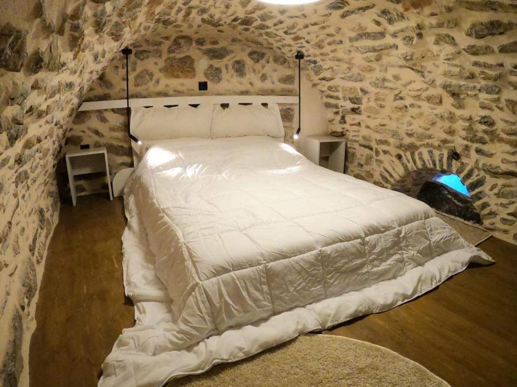 Sunday’s Holiday Houses في خيوس: غرفة نوم بسرير ابيض في جدار حجري