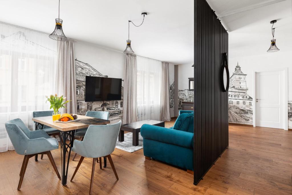 a living room with a dining room table and blue chairs at PEAK Aparthotel - Old Town - by CityHost in Braşov