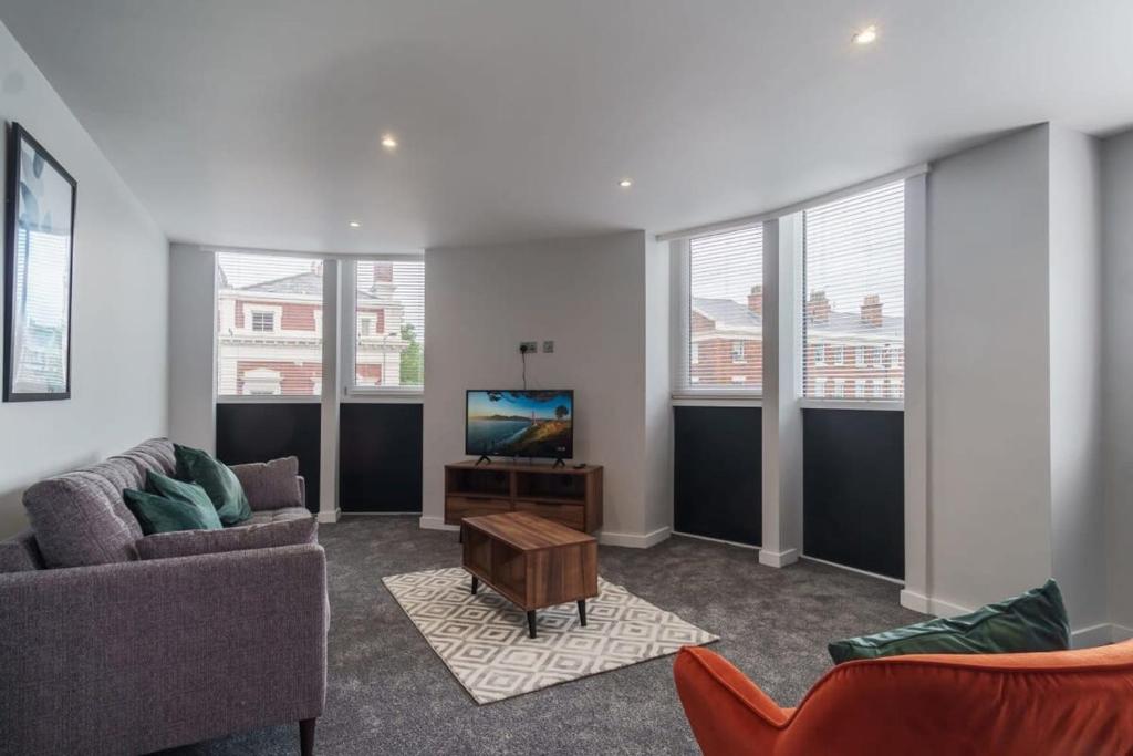 a living room with a couch and a tv and some windows at Modern 2 Bedroom Apartment in Liverpool in Liverpool